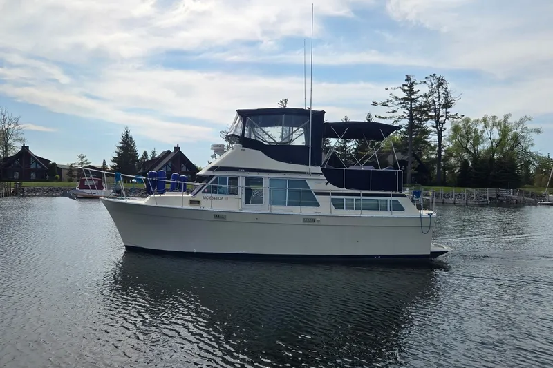 The Image of 1985 Tollycraft 34 Sundeck Motor Yacht on calm water, surrounded by trees and houses. - 0