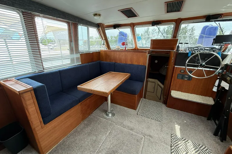 Slide: The Image of 1985 Tollycraft 34 Sundeck Motor Yacht interior with blue seating and wooden accents. - 27