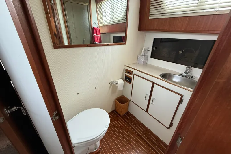 Slide: The Image of 1985 Tollycraft 34 Sundeck Motor Yacht bathroom with sink, toilet, and wood accents. - 29