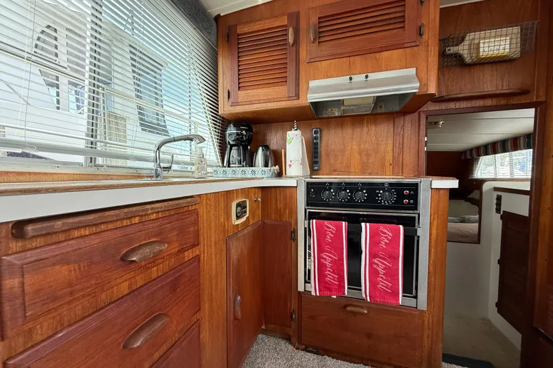 Slide: The Image of 1985 Tollycraft 34 Sundeck Motor Yacht kitchen with wood cabinetry and modern appliances. - 24