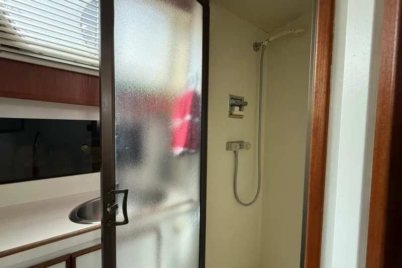 Slide: The Image of 1985 Tollycraft 34 Sundeck Motor Yacht shower area with frosted glass door and sink. - 30