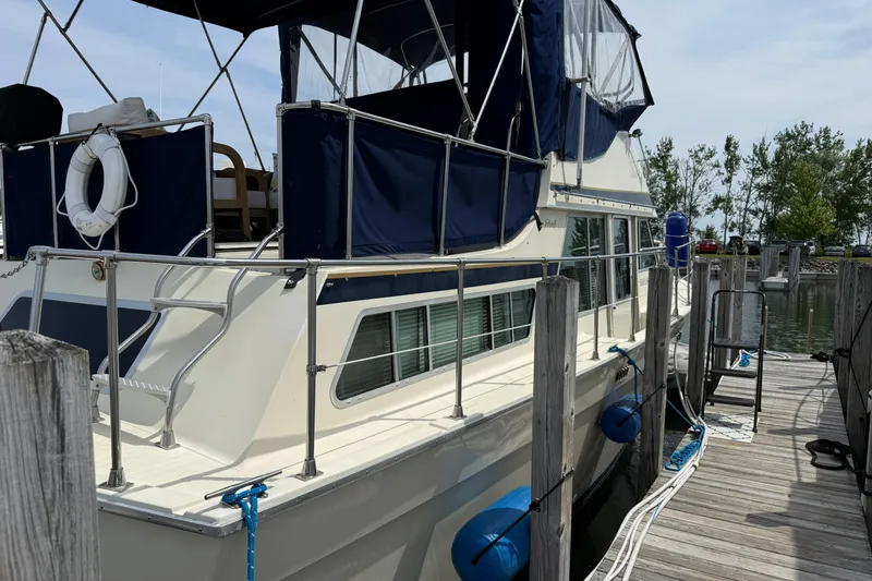 Slide: The Image of 1985 Tollycraft 34 Sundeck Motor Yacht docked, featuring blue canopy and white hull. - 2