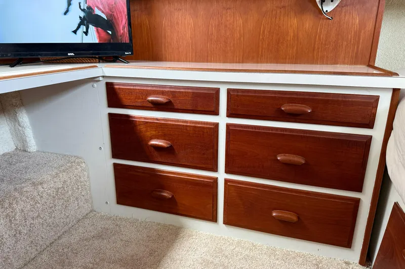Slide: The Image of 1985 Tollycraft 34 Sundeck Motor Yacht interior with wooden drawers and TV. - 35