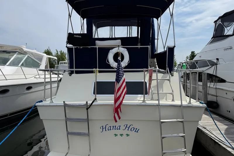 Slide: The Image of 1985 Tollycraft 34 Sundeck Motor Yacht docked, featuring "Hana Hou" name and American flag. - 1