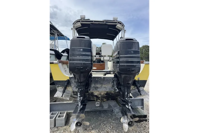 Slide: The Image of 1983 Boston Whaler 21 Outrage with dual outboard motors, parked on a gravel surface. - 8