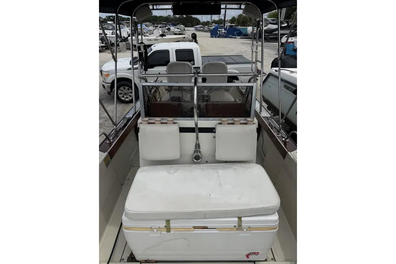 Slide: The Image of 1983 Boston Whaler 21 Outrage boat interior with seating and console, parked in a marina. - 16