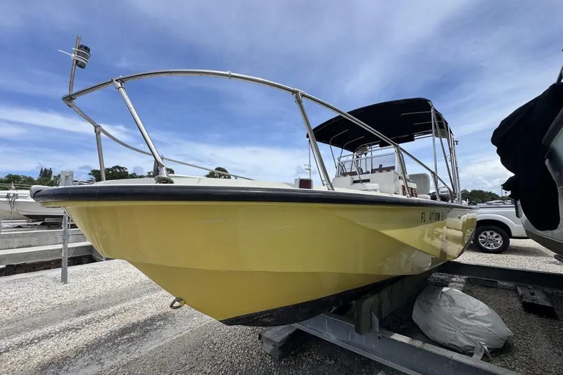 Slide: The Image of 1983 Boston Whaler 21 Outrage boat with yellow hull on a trailer, under a blue sky. - 3