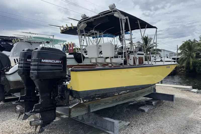 Slide: The Image of 1983 Boston Whaler 21 Outrage boat with dual Mercury engines, docked on a wooden platform. - 2