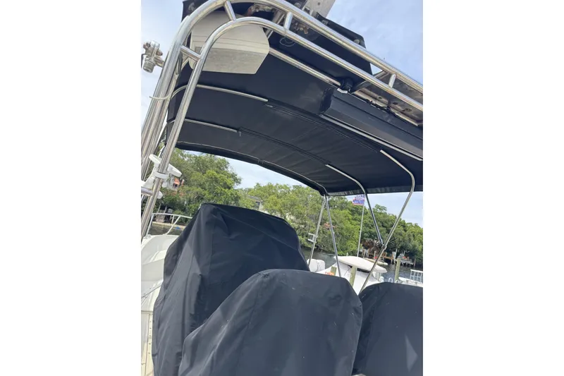 Slide: The Image of 1983 Boston Whaler 21 Outrage boat with covered seating and canopy, docked near trees. - 5
