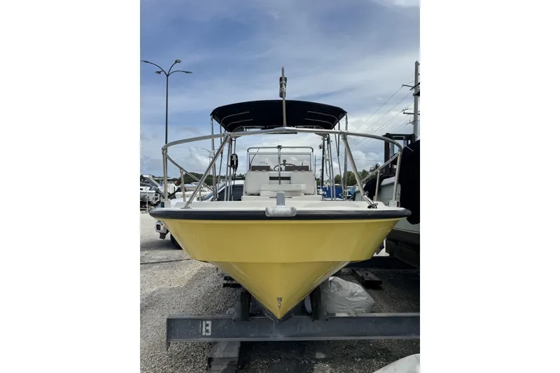 Slide: The Image of 1983 Boston Whaler 21 Outrage boat with yellow hull on trailer, under cloudy sky. - 6
