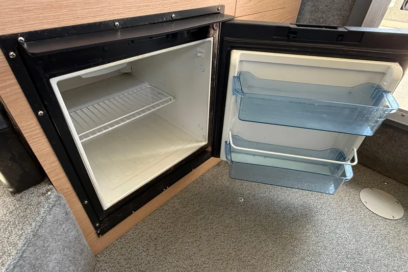 Slide: The Image of Open refrigerator inside 2018 Thunder Jet Pilot 26' boat, featuring empty shelves and door compartments. - 13