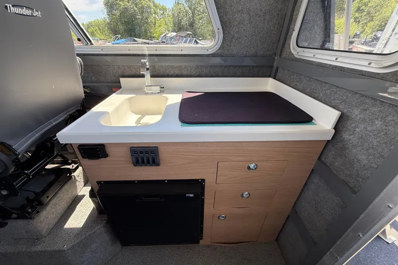 Slide: The Image of Interior of a 2018 Thunder Jet Pilot 26' boat featuring a compact kitchenette. - 12