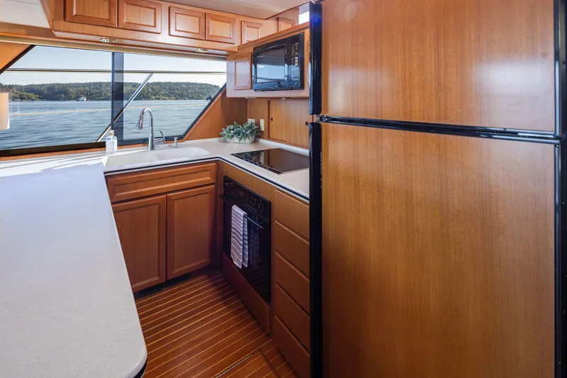 Slide: The Image of Luxurious kitchen interior of 2000 Symbol 50 Pilothouse yacht with wood cabinetry and scenic window view. - 5