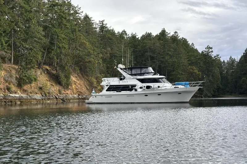 Slide: The Image of A 2000 Symbol 50 Pilothouse yacht anchored in a serene forested bay. - 35