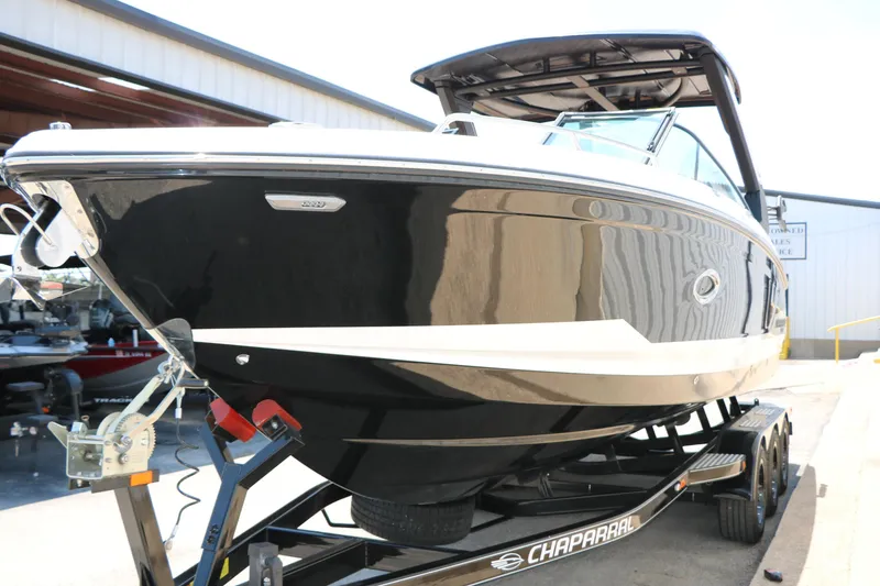 Slide: The Image of 2026 Chaparral 30 Surf boat on trailer, sleek black design, parked outdoors. - 18