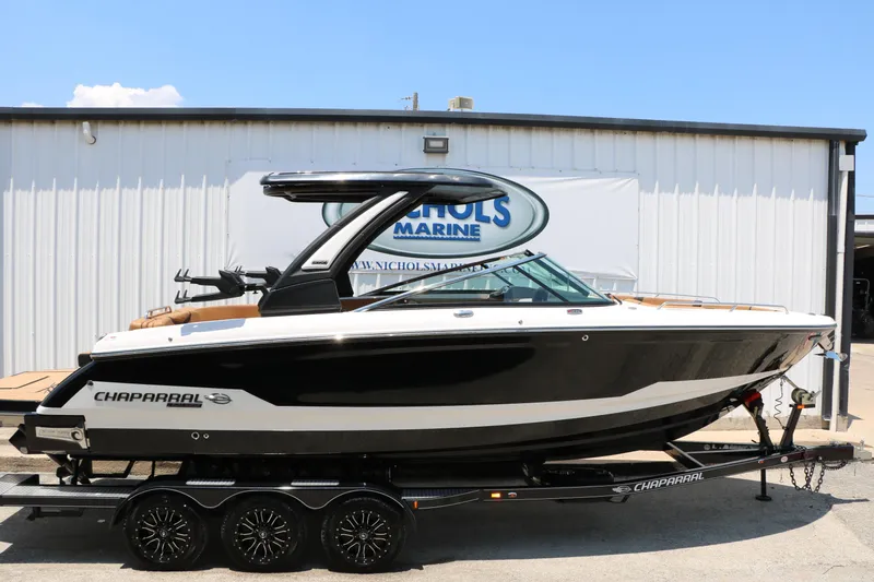 Slide: The Image of 2026 Chaparral 30 Surf boat on trailer, black and white design, parked outside Nichols Marine. - 3