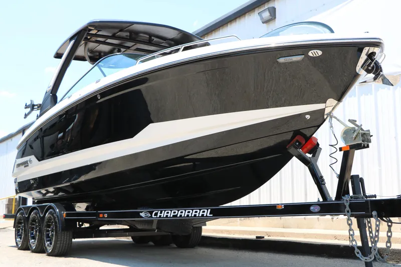 Slide: The Image of 2026 Chaparral 30 Surf boat on trailer, sleek black design, parked outdoors. - 5
