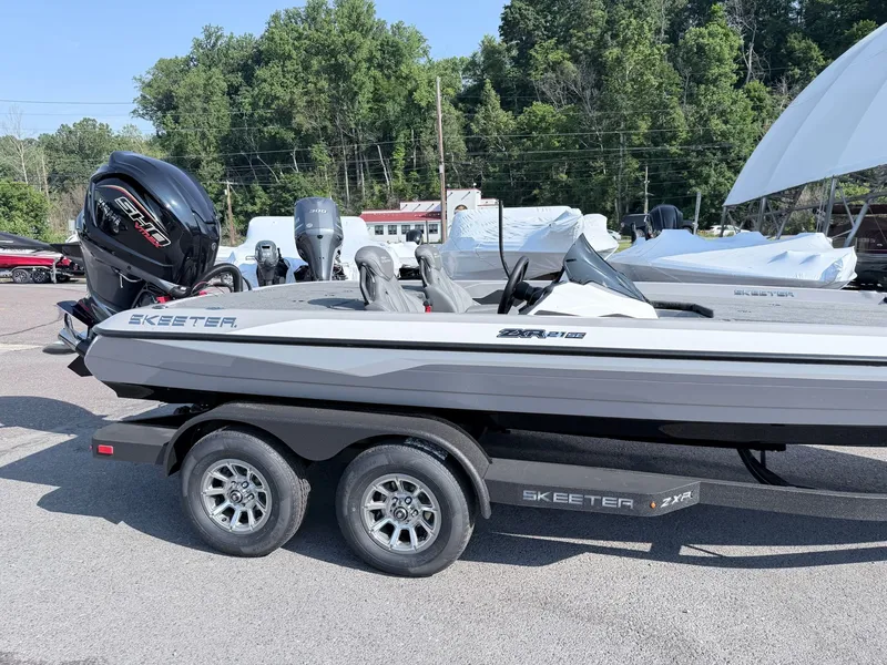 Slide: The Image of A gray Skeeter ZXR20 SE boat on a trailer, surrounded by trees and other boats. - 21