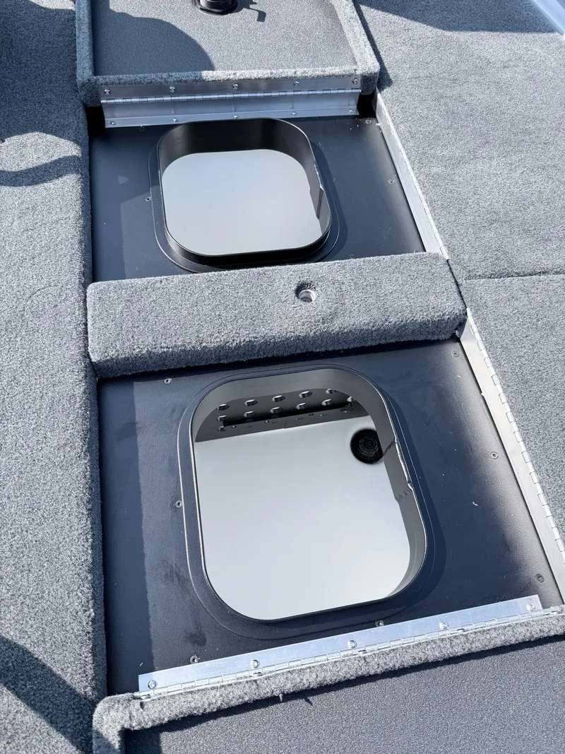 Slide: The Image of Two open storage compartments on a boat with gray carpeted flooring. - 36