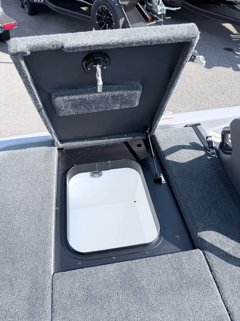 Slide: The Image of An open storage compartment on a 2026 Skeeter ZXR20 SE boat, featuring gray carpeting. - 10