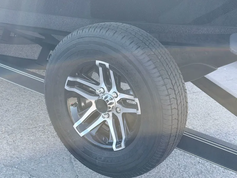 Slide: The Image of Close-up of a boat trailer wheel with a shiny rim on asphalt. - 15