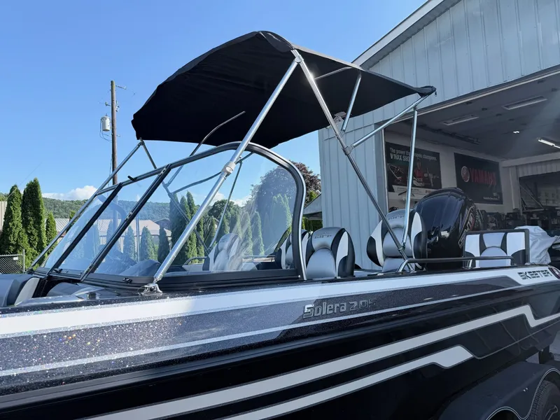 Slide: The Image of The image shows a modern boat with a black sunshade, situated in a harbor area. - 26