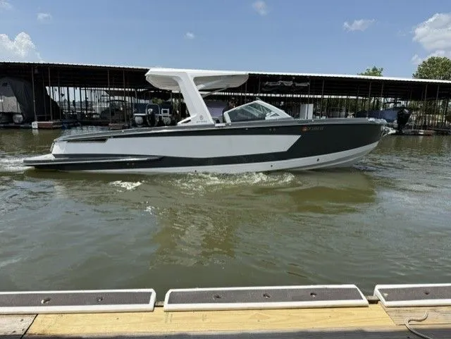 The Image of A 2021 Aviara AV32 boat cruising on calm water near a covered dock. - 1