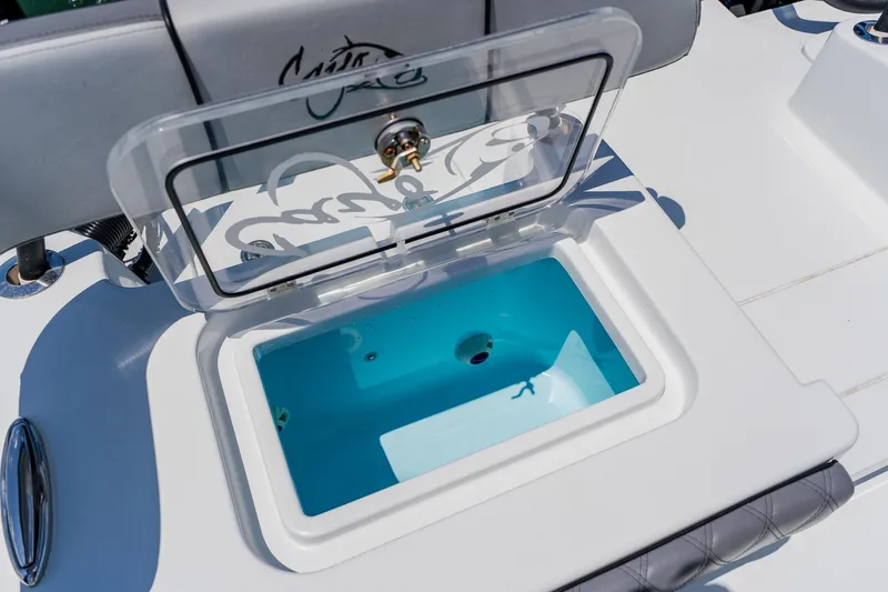 Slide: The Image of Open storage compartment on 2021 Costa Custom Boats 264HC, featuring a clear lid and blue interior. - 92
