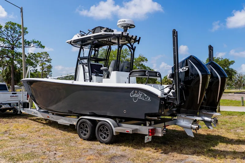 Slide: The Image of 2021 Costa Custom Boats 264HC on trailer, dual engines, parked outdoors under blue sky. - 1