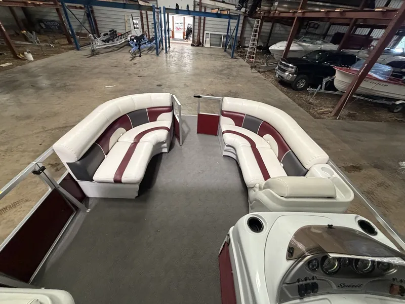 Slide: The Image of Interior view of a JC Spirit pontoon boat with white and red seating in a warehouse. - 6