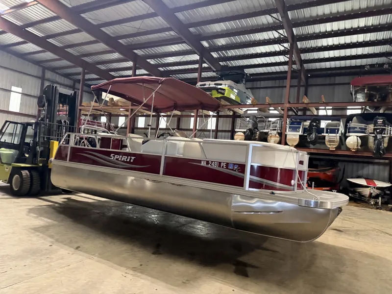 The Image of A red pontoon boat with a sunshade is in a warehouse. - 1