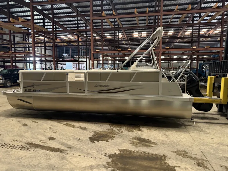 Slide: The Image of A pontoon boat is in a warehouse on a trailer. - 16