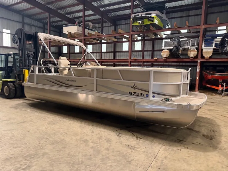Slide: The Image of A silver pontoon boat is in a warehouse, surrounded by other boats and a forklift. - 23