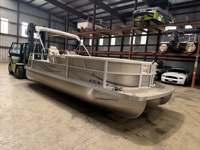 Slide: The Image of A pontoon boat is in a warehouse, surrounded by other boats and a forklift. - 18