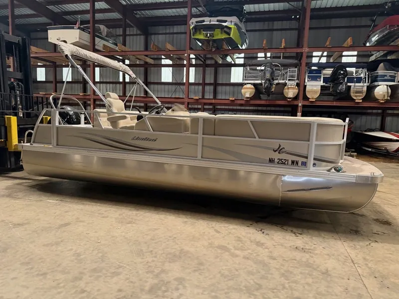 Slide: The Image of A silver pontoon boat is in a warehouse. It features a canopy and seating. - 10