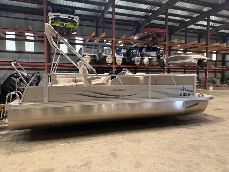 Slide: The Image of A silver pontoon boat is in a warehouse, surrounded by other boats. - 12