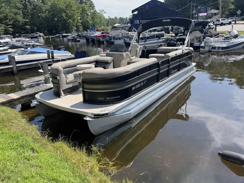 Slide: The Image of A 2014 Premier 240 SunSation pontoon boat is docked. It features black sides and beige seating. - 5