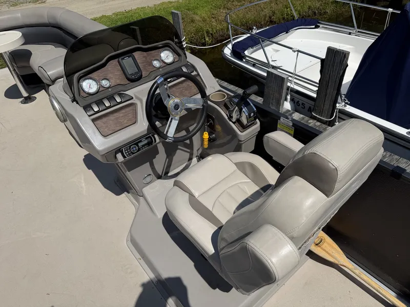 Slide: The Image of The image shows the cockpit of a 2014 Premier 240 SunSation pontoon boat with beige seating. - 8