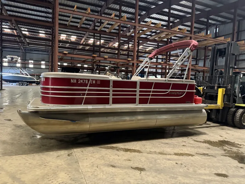 Slide: The Image of A red Starcraft pontoon boat in a warehouse. - 17