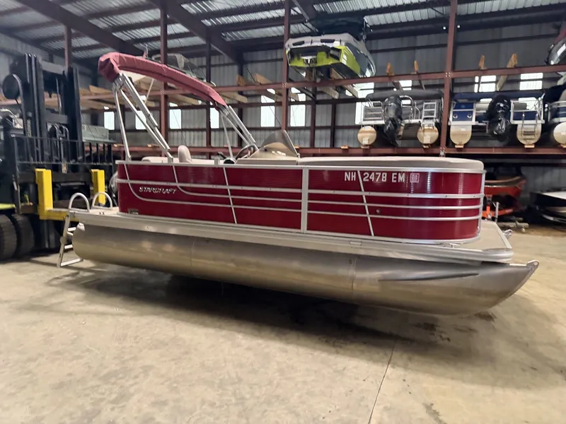 Slide: The Image of A red 2014 Starcraft pontoon boat is in a warehouse. - 13