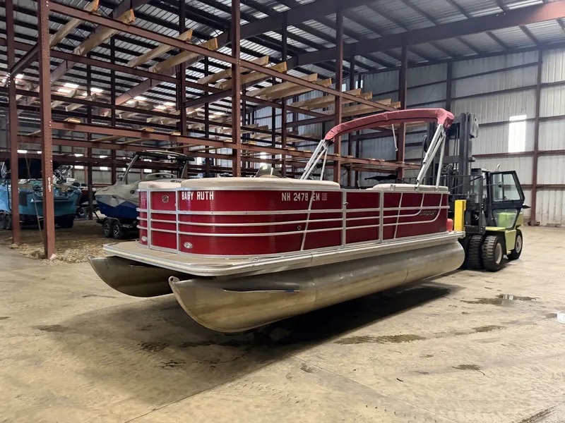 Slide: The Image of A red pontoon boat in a warehouse, featuring a covered canopy and sturdy aluminum hull. - 15