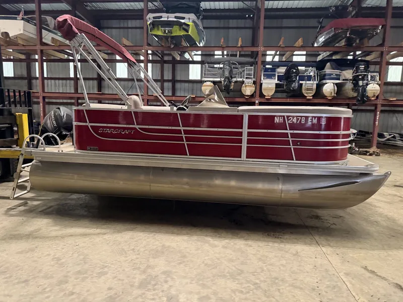 The Image of A red 2014 Starcraft pontoon boat is in a storage facility. - 1