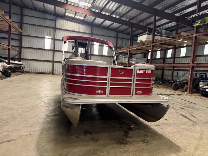 Slide: The Image of A red Starcraft pontoon boat in a storage warehouse. - 2