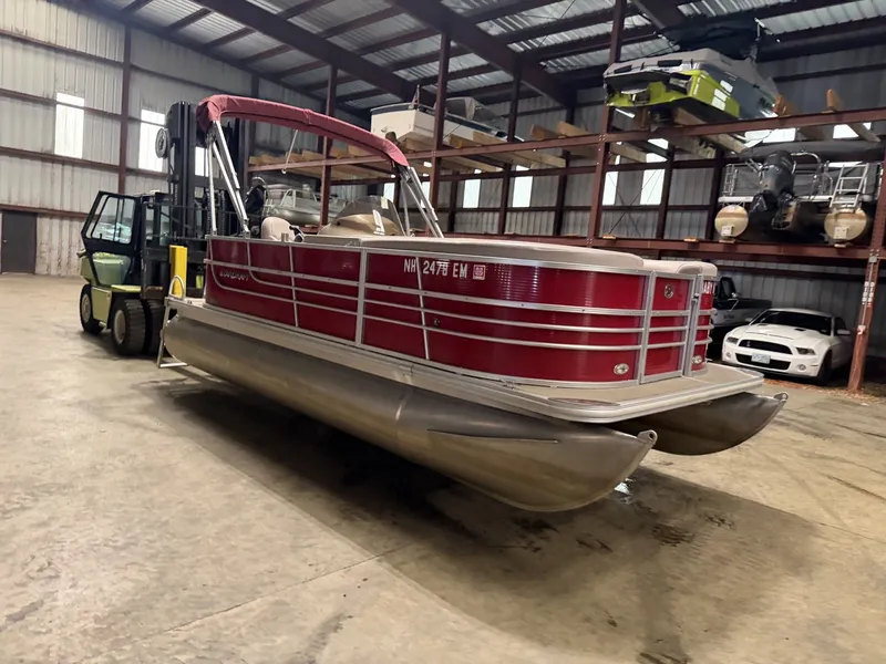 Slide: The Image of A red Starcraft pontoon boat in a warehouse, next to a forklift. - 6