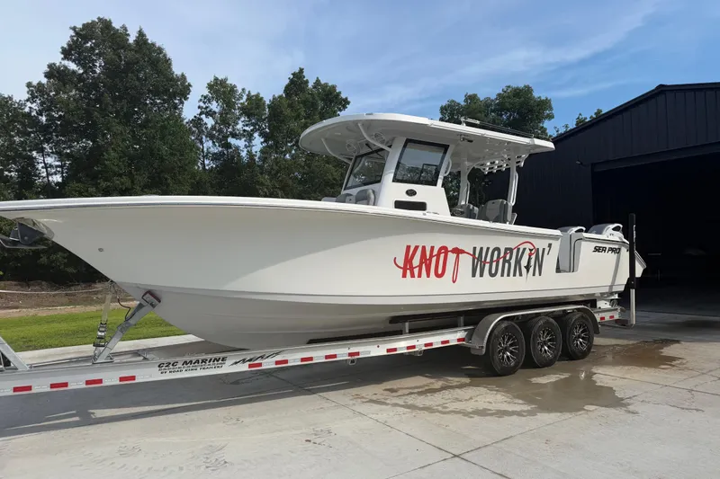 Slide: The Image of 2024 Sea Pro 322 Offshore boat on trailer, labeled "Knot Workin'," parked outdoors. - 3