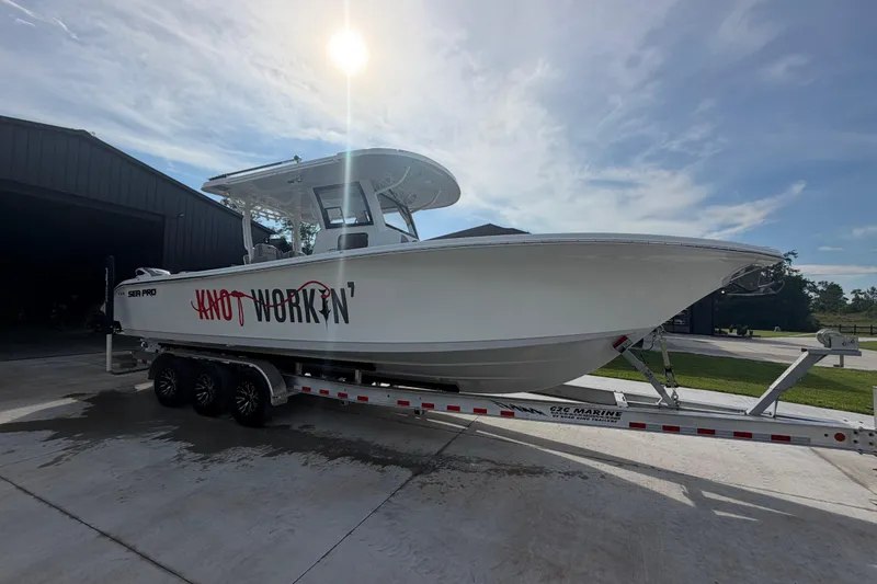 Slide: The Image of 2024 Sea Pro 322 Offshore boat on trailer, labeled "Knot Workin'," under sunny sky. - 5