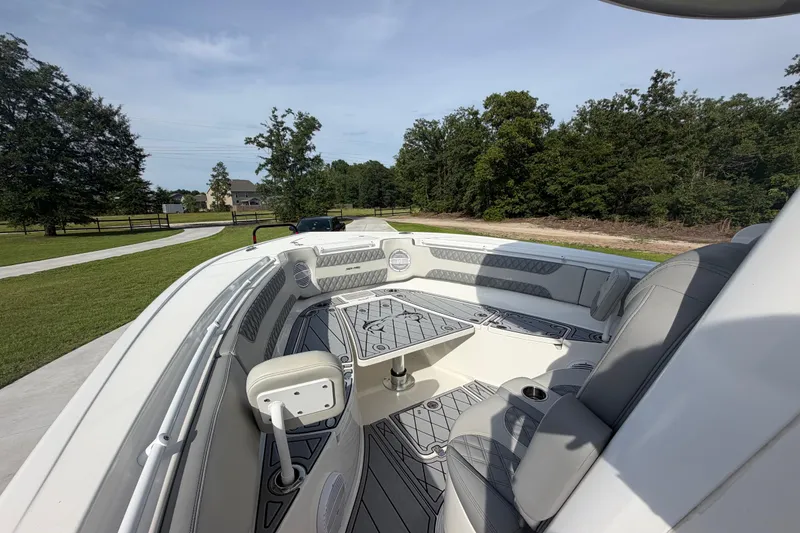 Slide: The Image of 2024 Sea Pro 322 Offshore boat interior with seating and table, surrounded by greenery. - 9