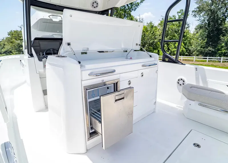 Slide: The Image of The 2027 Wellcraft 28 T-Top features a modern outdoor kitchen with a fridge and storage space. - 19