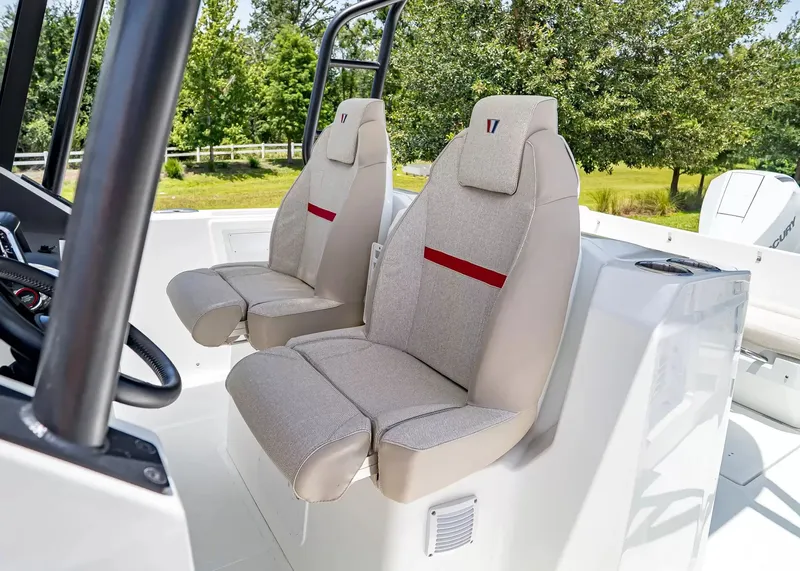 Slide: The Image of Two beige seats with red stripes on a Wellcraft 28 T-Top boat, surrounded by green landscape. - 20