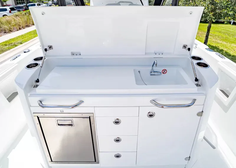 Slide: The Image of The 2027 Wellcraft 28 T-Top features a sleek outdoor kitchen with a sink and storage. - 16